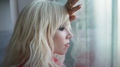 a woman with long blonde hair and ring on her head looking out the window at something outside