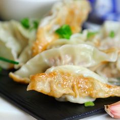 some dumplings are sitting on a black plate