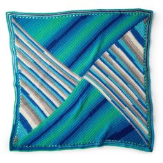 a blue and white striped square on top of a green pillow with two different colored stripes