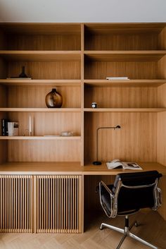 an office with wooden shelves and a black chair in front of the desk is a bookshelf