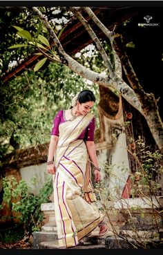 a woman in a white and purple sari walking up steps with her hand on her hip