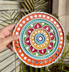 a hand holding a colorful plate with designs on it