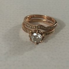 two gold wedding rings with a diamond on the top and bottom, sitting on a white surface