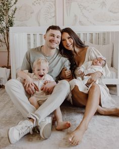 a man, woman and baby are sitting on the floor in their crib together