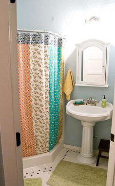 a bathroom with a sink, shower curtain and rugs on the floor in it