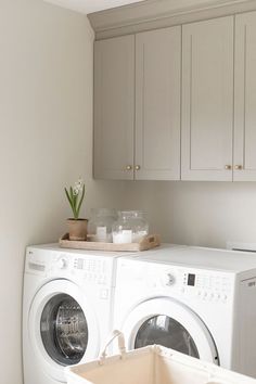 a white washer and dryer in a room with wooden cabinets on the wall