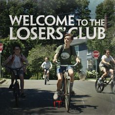 a group of people riding bikes down a street next to a sign that says welcome to the losers'club