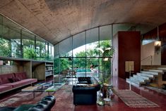 a living room filled with lots of furniture next to a large glass wall covered in windows