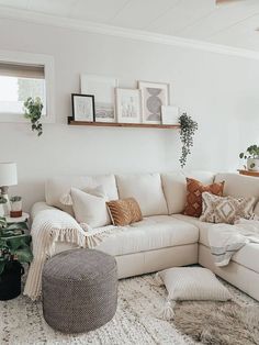 a living room filled with lots of furniture and plants on top of a white rug