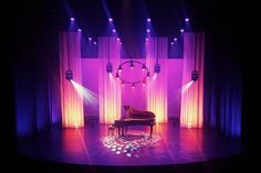 a grand piano on stage with purple lighting