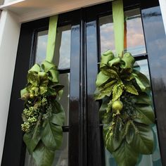 two green wreaths are hanging on the front door