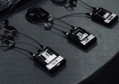 four electronic devices connected to each other on top of a gray table with wires and plugs