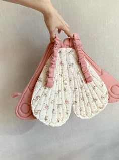 a hand holding a pink and white fan shaped purse with ruffles on it