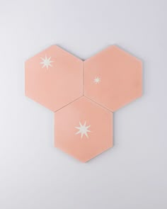 three pink hexagonals with white stars on them against a gray background,