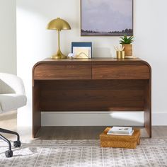 a desk with a lamp and some pictures on it in a room that has white walls