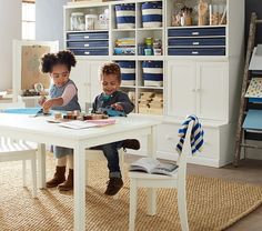 two young children sitting at a table in front of a chalkboard on the wall