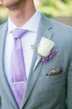 a man in a gray suit with a purple tie and white rose boutonniere