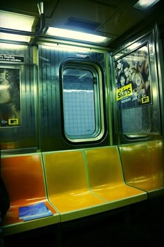 an empty subway car with yellow seats and posters on the wall