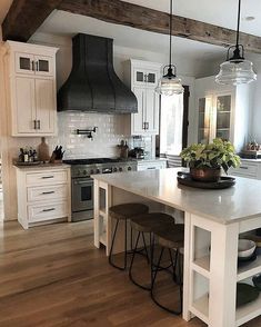 a kitchen with white cabinets and an island in the middle, surrounded by stools