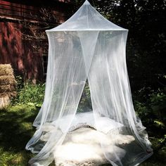 a white bed sitting on top of a lush green field