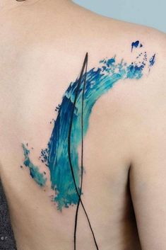 the back of a woman's shoulder with an abstract blue wave tattoo on it