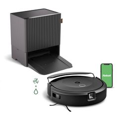 the robot vacuum is next to an appliance with its lid open and it's charging cord attached