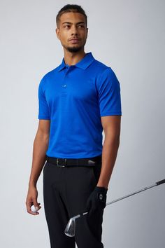 a male in a blue shirt and black pants is holding a golf clubs club while posing for the camera