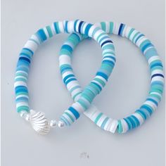 two bracelets with blue and white striped beads on each strand, one has a seashell charm