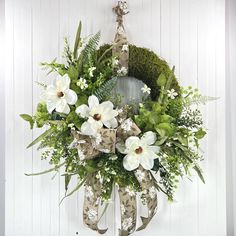 Welcome timeless elegance to your home with this exquisite white magnolia wreath. Featuring a large moss wreath base and lifelike magnolia blooms nestled among lush greenery, this design is further enhanced by charming ribbon adorned with a delicate floral motif.  Its generous size and natural color palette make it the perfect statement piece for your front door, entryway, or living space. Whether for spring or year-round decor, this wreath embodies sophistication and farmhouse charm. Create a w Farmhouse Door Hanger, Front Door Spring, Moss Wreath, Farmhouse Door, Door Bumper, Door Entryway, Wreath Base, Magnolia Wreath, Magnolia Blossom