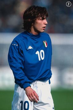 a soccer player is standing on the field with his hands in his pockets and looking down