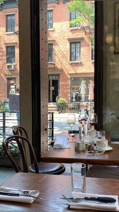 a woman sitting at a table in front of a window looking at her cell phone