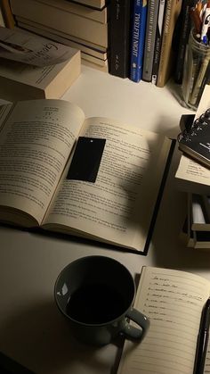 an open book sitting on top of a table next to a cup of coffee and books