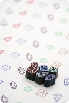 several different colored diamond shaped rubber stamps on a white surface with multicolored diamonds in the background