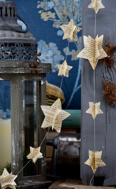 some paper stars hanging from a string next to a lantern and candle holder on a table