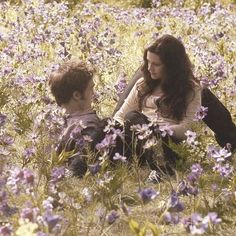 a woman and child sitting in a field of flowers