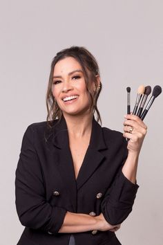 a woman is holding brushes in one hand and smiling