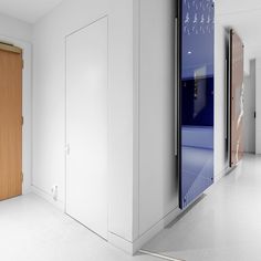 an empty room with white walls and wooden doors on the wall are two different colored doors