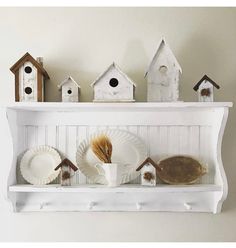 a shelf filled with bird houses and plates on top of white shelves next to each other