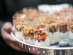 desserts are served in small glasses on a silver tray