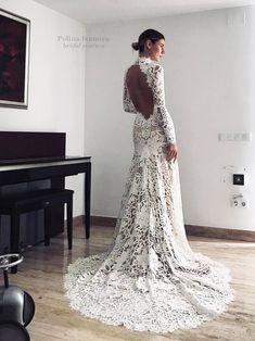 a woman standing in front of a piano wearing a dress with long sleeves and open back