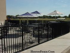 tables and umbrellas are set up on the side of a fenced in area