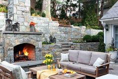 an outdoor fireplace and seating area with flowers in vases on the table next to it