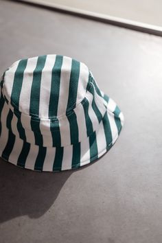 The hat is a stylish and comfortable accessory that is perfect for any casual outfit. Made from 100% cotton, it is breathable and soft to the touch. The green and white lines add a pop of color and a touch of personality, making it a unique and eye-catching piece. Matching set: Green Striped Denim Effect Kalina Shirt Green And White Striped Bucket Hat, White Cotton Bucket Hat For Summer, White Cotton Summer Sun Hat, White Cotton Summer Hat, White Cotton Bucket Hat For Vacation, Trendy Cotton Sun Hat With Flat Brim, White Cotton Sun Hat With Short Brim, Summer Cotton Cap, White Cotton Vacation Hat