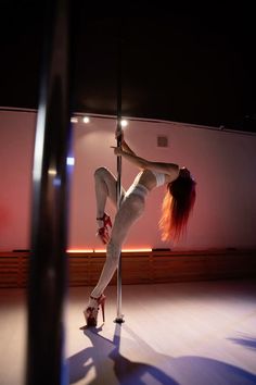 a woman is doing pole dancing in the dark