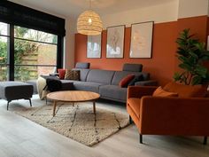 an orange and grey living room with two couches, a coffee table and a large window