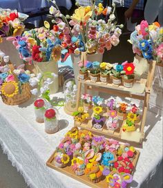 an assortment of colorful cupcakes and flowers on display at a vendor's table