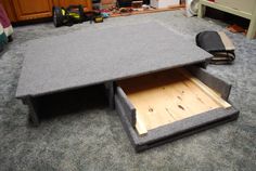 an open drawer on the floor in a room with carpeted floors and cabinets around it