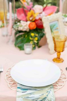 a white plate sitting on top of a table next to a vase filled with flowers