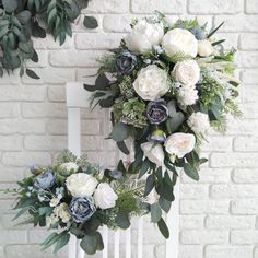 two white and blue flowers are sitting on a chair next to a brick wall with greenery