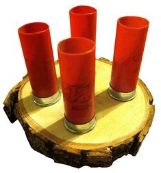 four red candles sitting on top of a tree stump